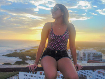 Turista bonita, apreciando o pôr do sol na praia em arraial do cabo