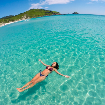 Turista em biquíni nadando nas águas transparentes em arraial do cabo