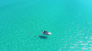 Barco no meio da água cristalina de arraial do cabo durante a caminhada