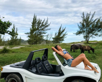 Turista em biquíni tomando sol em um bugre branco em arraial do cabo