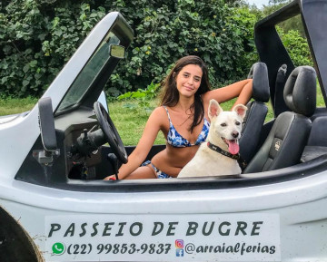 Turista bonita com seu cão dentro de um bugre branco em arraial do cabo