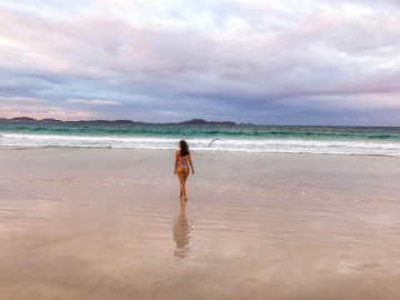 Bela morocha tursta andando na praia de arraial do cabo em suas férias