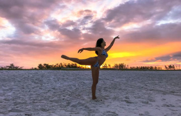 Turista de mulher bonita, vagando na praia com um incrível pôr do sol por trás dela em arraial do cabo
