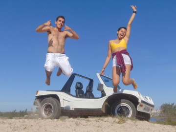 Turistas pulando na praia e atrás deles você vê um buggy branco no arraial do cabo