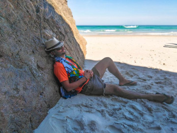 Turista dormindo em uma pedra na praia de arraial do cabo durante suas férias