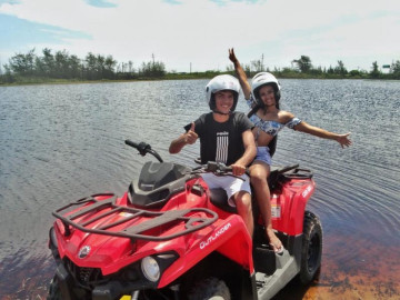 Casal apaixonado andando na praia de Arraial do Cabo com quadriciclo vermelho de Arraial Ferias