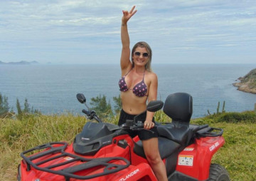 Linda jujer em mesh andando de quadriciclo vermelho acenando para a câmera fotográfica em arraial do cabo