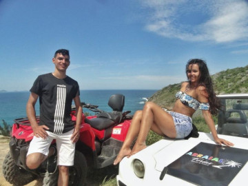 Um casal de noivos curtindo a vista da praia de Arraial do Cabo em um ponto panorâmico de um belo morro com quadriciclo e buggy alugado em Arraialferias