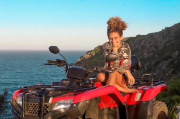 Uma linda jovem, tirando foto em um parador ou ponto panorâmico de Arraial do Cabo com seu quadriciclo alugado em Arraialferias