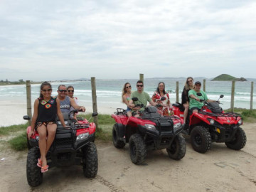 6 Pessoas aproveitam seus quadriciclos alugados em Arraialferias estacionados em um hostel em Arraial do Cabo em suas férias